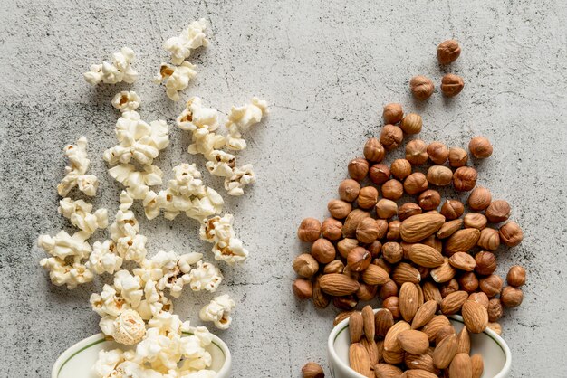 Pop-corn et fruits secs tombés d&#39;un bol sur un fond en béton