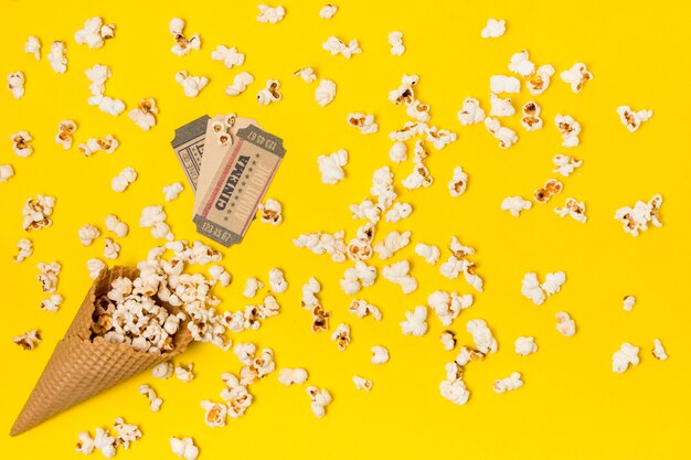 Popcorns renversés du cône de gaufres avec billet de cinéma