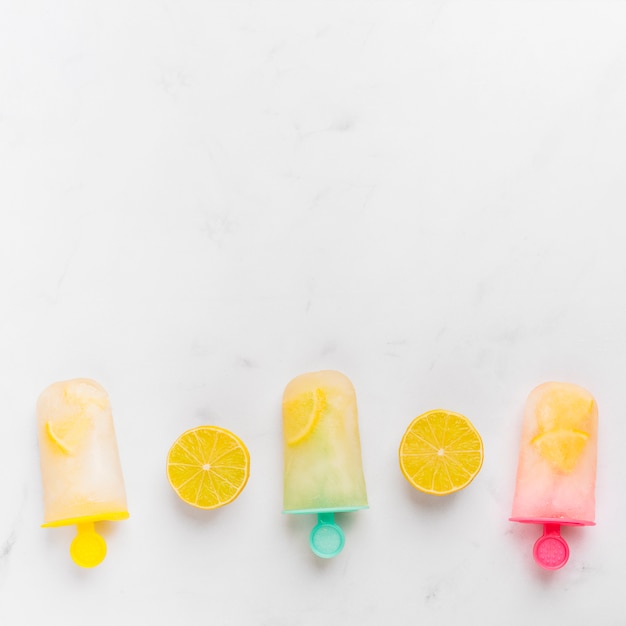 Photo gratuite popsicle tranché au citron et glace avec agrumes sur des bâtons colorés