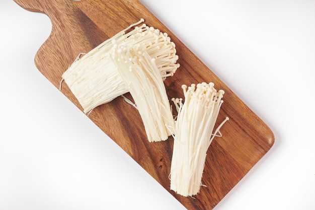 Populaire dans la cuisine asiatique champignon aiguille d'or frais ou enoki, enokitake sur planche à découper en bois. Vue de dessus. Mise à plat. Fraîchement du jardin biologique de croissance à domicile. Concept de nourriture.