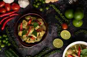 Photo gratuite porc au curry vert dans un bol brun avec des épices sur un fond de ciment noir