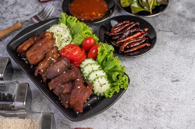 Photo gratuite porc frit garni de sésame placé dans un plat noir.