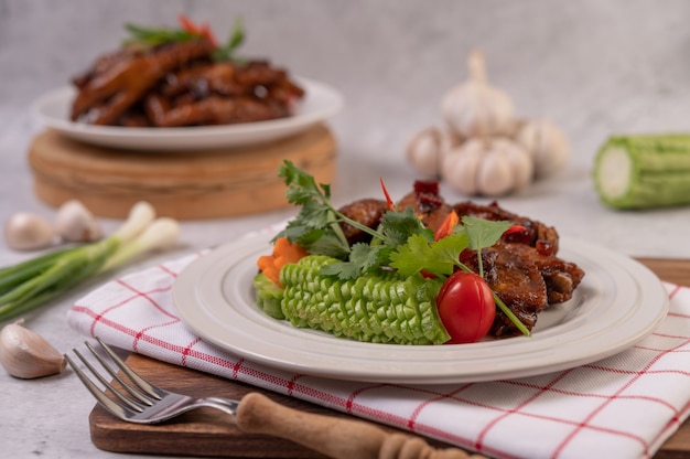 Porc sucré dans une assiette blanche avec oignons verts hachés, piment, citron vert, courge, tomate et ail.