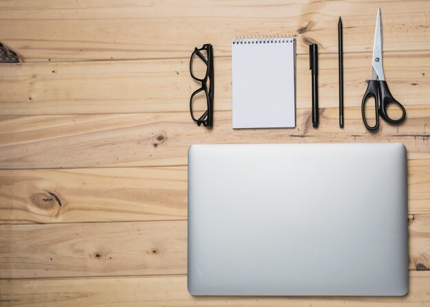 Portable; papeterie et lunettes sur une surface en bois