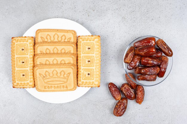 Une portion de biscuits à côté d'une petite portion de dattes sur fond de marbre. Photo de haute qualité