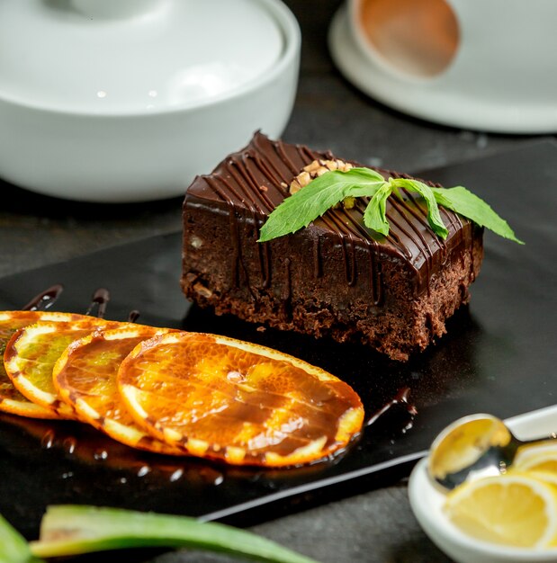 Portion de brownie au chocolat servi avec une tranche d'orange