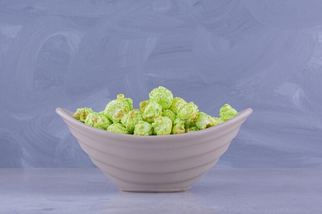 Une portion croustillante de bonbons au pop-corn dans un petit bol sur fond de marbre. photo de haute qualité