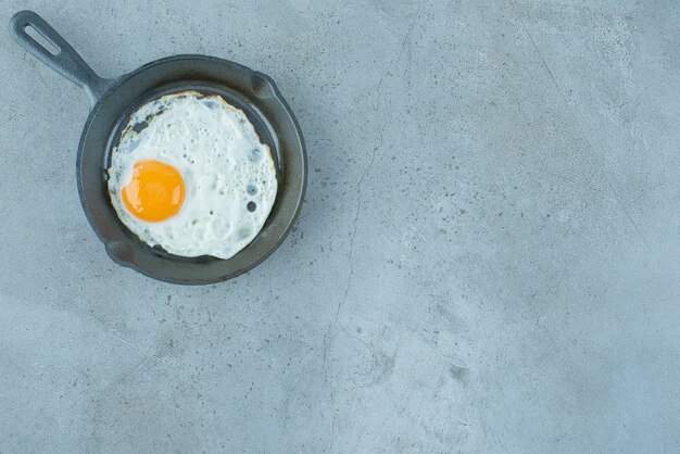 Une portion d'oeuf au plat dans une casserole sur fond de marbre. Photo de haute qualité