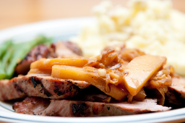 Portion de porc rôti appétissant recouvert de cidre et de compote de pommes épaisse