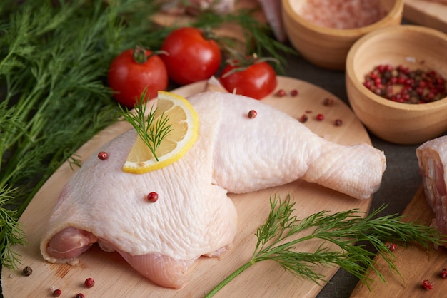 portions de viande de poulet fraîche pour la cuisson et le barbecue avec assaisonnement frais. Cuisse de poulet cru cru sur une planche à découper.