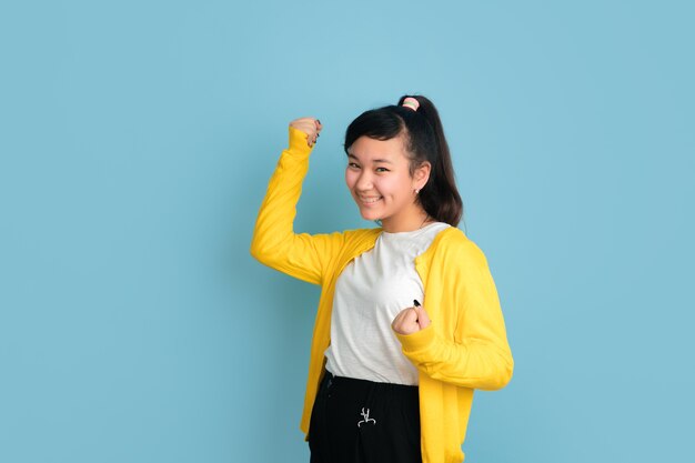 Portrait d'adolescent asiatique isolé sur l'espace bleu. Beau modèle femme brune aux cheveux longs