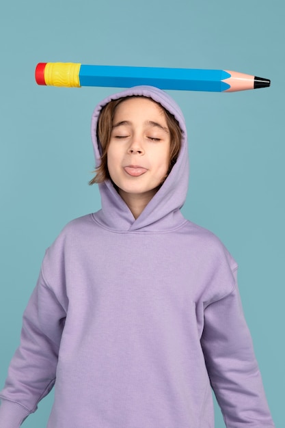 Photo gratuite portrait d'un adolescent portant un gros crayon sur la tête et gardant sa langue dehors