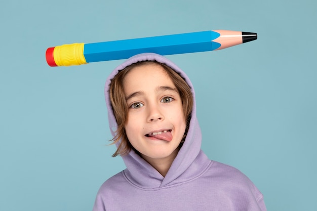 Photo gratuite portrait d'un adolescent portant un gros crayon sur la tête et gardant sa langue dehors