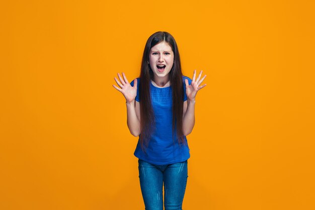 Portrait d'adolescente en colère sur un studio orange