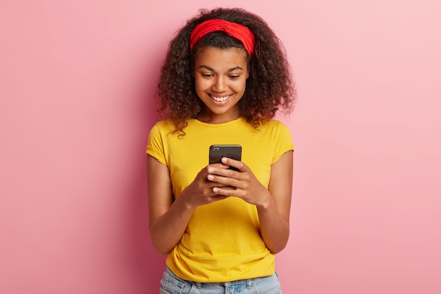 Portrait d'adolescente heureuse aux cheveux bouclés posant en tshirt jaune