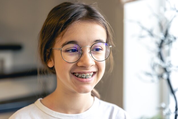 Portrait d'une adolescente avec des lunettes et un appareil dentaire