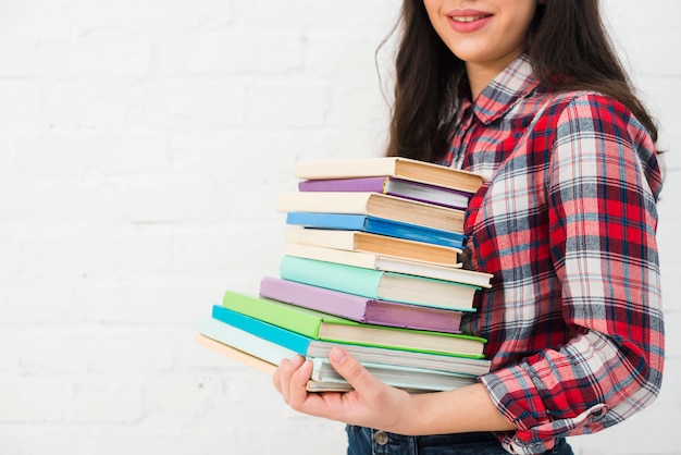 Portrait d&#39;adolescente avec une pile de livres