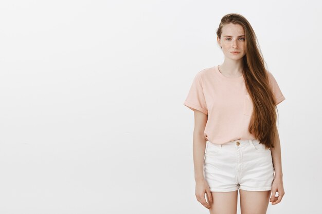 Portrait d'adolescente posant contre le mur blanc