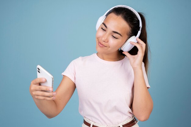 Portrait d'une adolescente utilisant des écouteurs et un smartphone