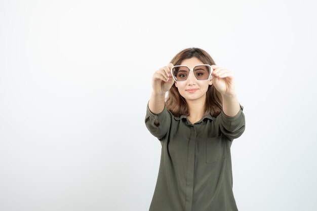 Portrait d'adorable jeune femme tenant des lunettes sur blanc. Photo de haute qualité