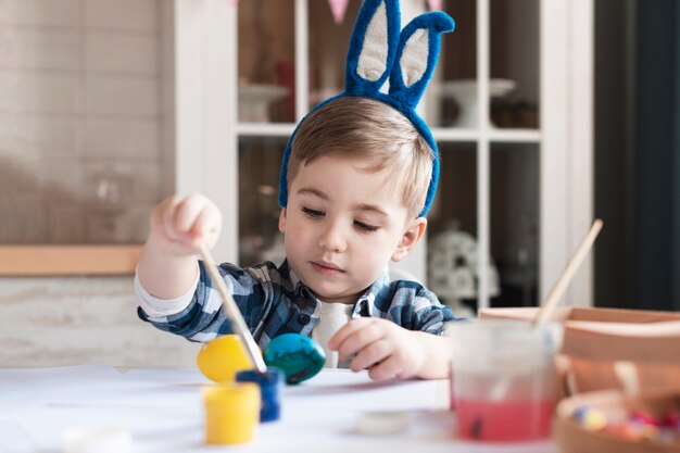 Portrait de l'adorable petit garçon peignant des oeufs pour Pâques