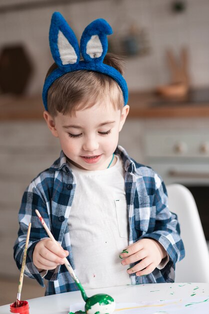Portrait de l'adorable petit garçon peignant des oeufs pour Pâques