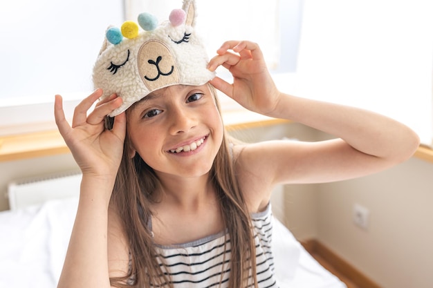 Portrait d'adorable petite fille s'est approchée de son lit le matin ensoleillé