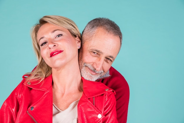 Photo gratuite portrait affectueux de souriant couple d'âge mûr sur fond turquoise