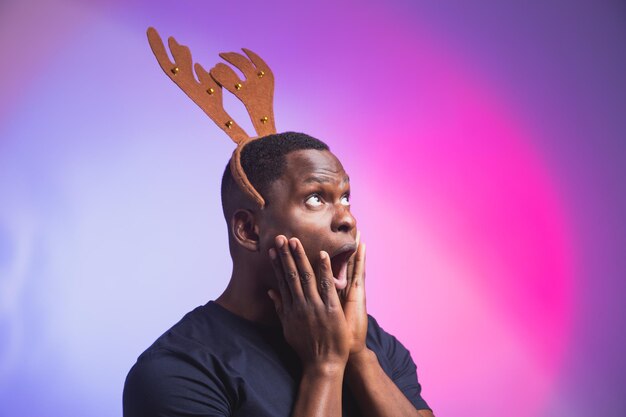 Portrait d'un afro-américain surpris émotionnellement portant des cornes de cerf rudolph profiter de son accessoire
