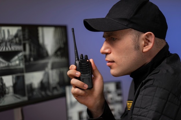 Photo gratuite portrait d'un agent de sécurité masculin avec une station de radio et des écrans de caméra