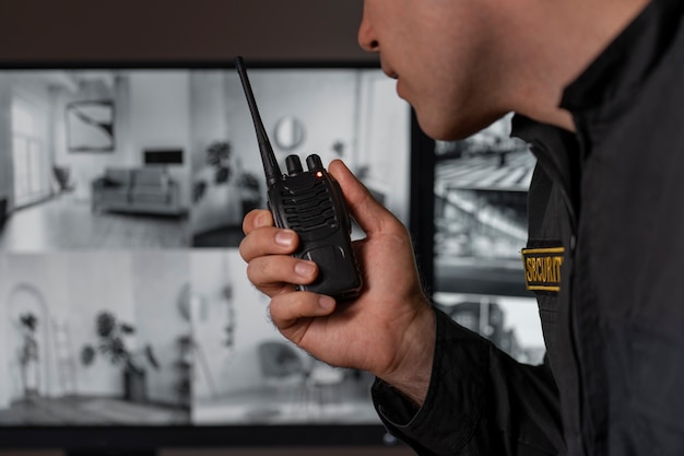 Portrait d'un agent de sécurité masculin avec une station de radio et des écrans de caméra