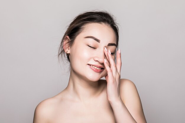 Portrait agrandi de femme asiatique beauté visage. Beau modèle féminin asiatique de race mixte attrayant avec une peau parfaite isolé sur mur gris