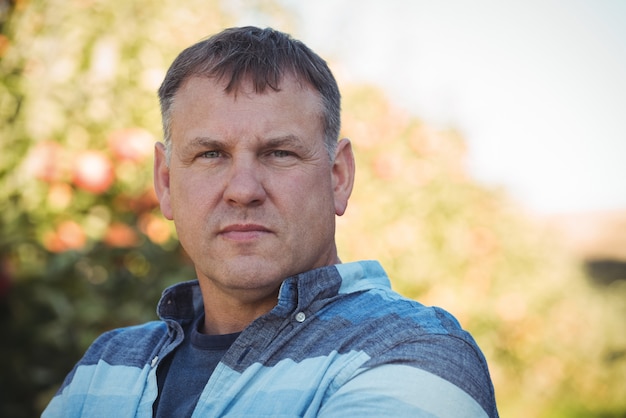 Portrait d'agriculteur debout dans un verger de pommiers