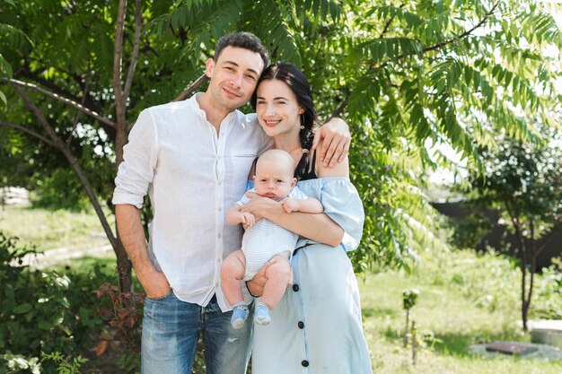 Portrait d&#39;aimer jeune couple avec leur bébé debout dans le parc