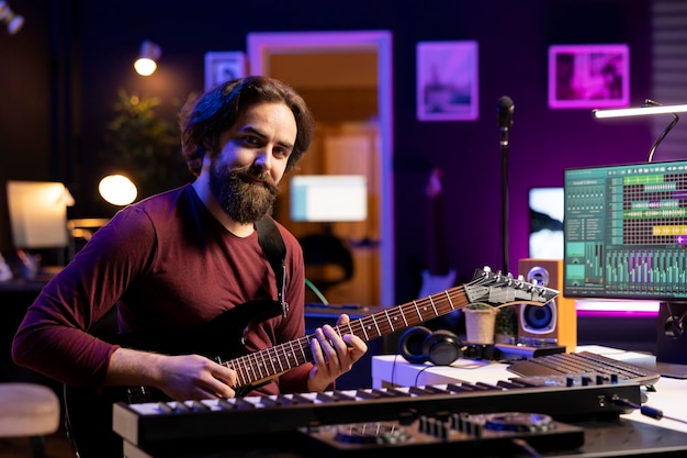 Photo gratuite portrait d'un artiste confiant jouant de la guitare acoustique dans son studio à la maison