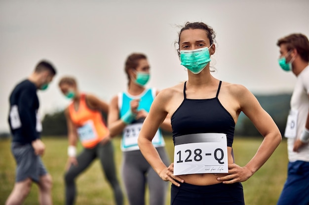 Portrait d'une athlète féminine portant un masque facial tout en participant à une course de marathon pendant la pandémie de COVID19