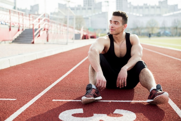 Portrait d'athlète masculin se détendre sur la piste de course rouge