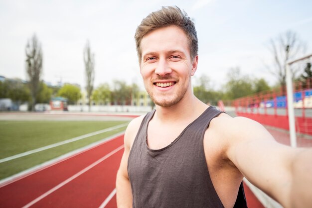 Portrait d'athlète masculin souriant parlant de selfie sur téléphone mobile