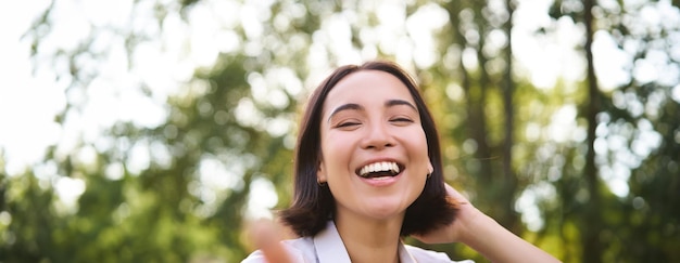 Photo gratuite portrait authentique d'une femme asiatique qui rit et sourit en se promenant dans le parc en se sentant heureuse et