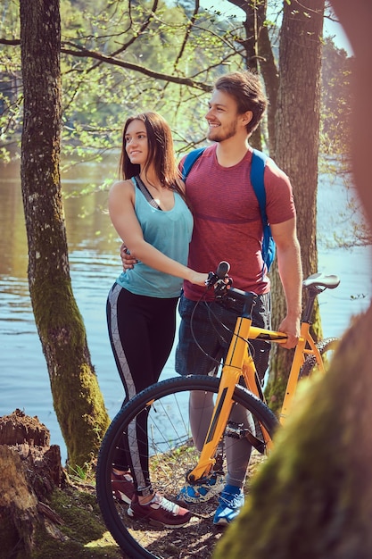 Photo gratuite portrait d'un beau couple. un couple souriant se détend en se tenant debout au bord du lac dans les bois.