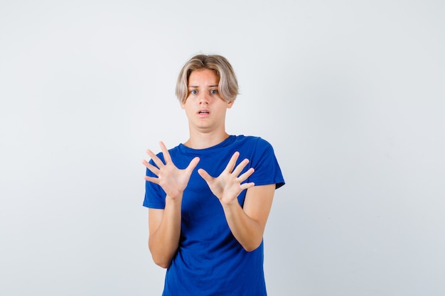 Photo gratuite portrait d'un beau garçon adolescent montrant un geste d'abandon en t-shirt bleu et regardant la vue de face effrayée