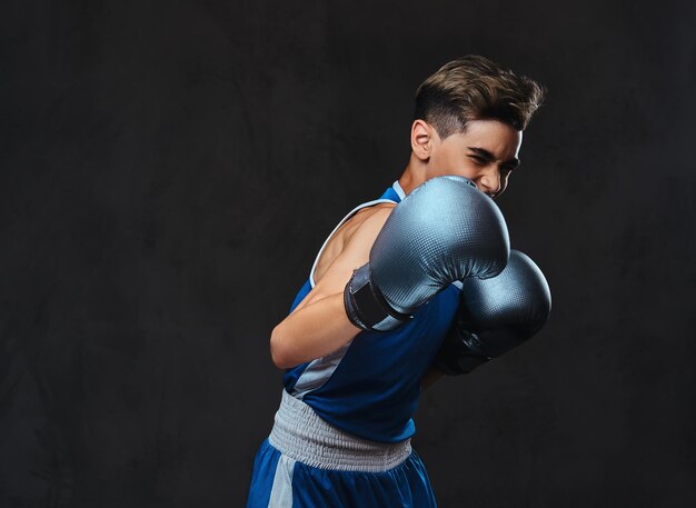 Portrait d'un beau jeune boxeur lors d'exercices de boxe, axé sur le processus avec un soin du visage sérieux et concentré.