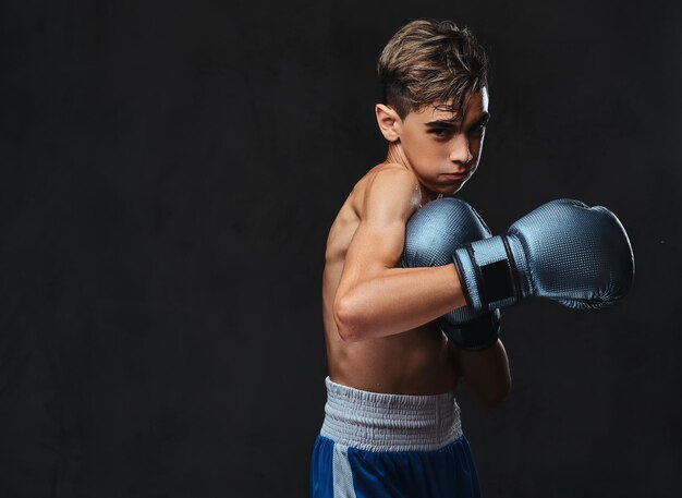 Portrait d'un beau jeune boxeur torse nu pendant les exercices de boxe, concentré sur le processus avec un soin du visage concentré sérieux.