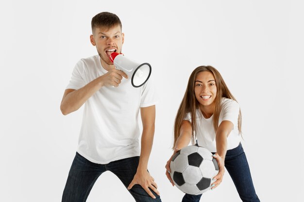 Portrait de beau jeune couple fans de football ou de football sur studio blanc