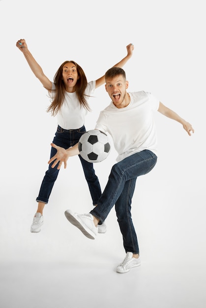 Portrait de beau jeune couple isolé sur fond de studio blanc. Expression faciale, émotions humaines, publicité, paris, concept sportif. Homme et femme jouant au football ou au football en action.