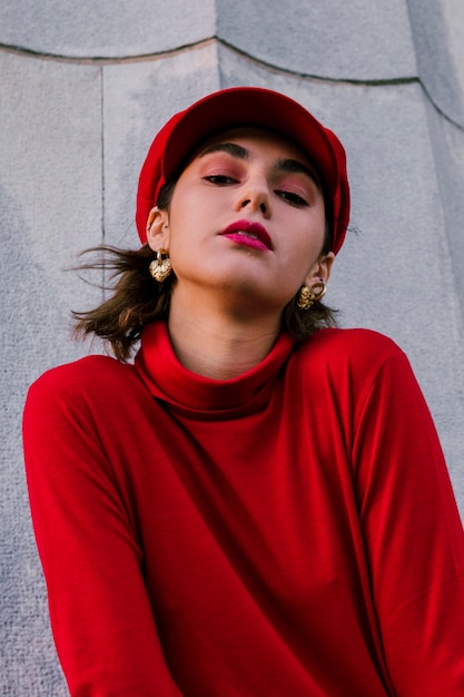 Photo gratuite portrait, de, a, beau, jeune femme, dans, casquette rouge, et, debout, haut, devant, mur