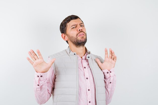 Portrait d'un beau jeune homme montrant un geste d'abandon en chemise, gilet et à la vue de face réticente