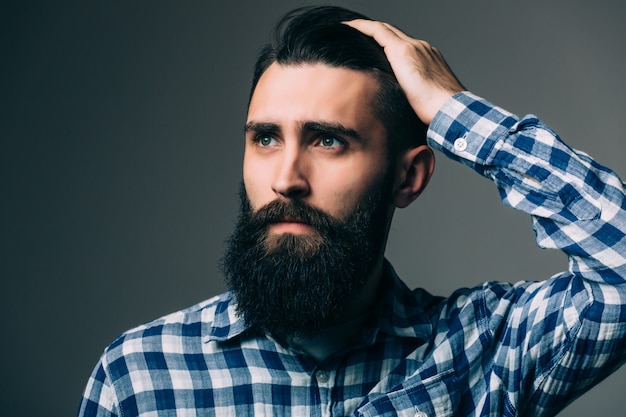 Portrait de beau jeune homme pensant isolé sur mur gris