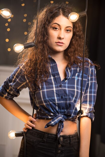 Portrait d'un beau jeune mannequin en chemise à carreaux posant près des lampes