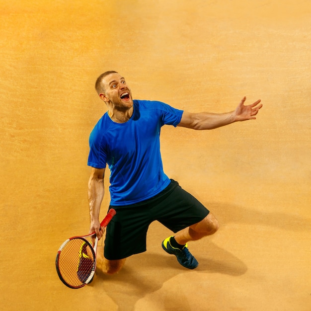 Portrait d'un beau joueur de tennis masculin célébrant son succès sur un mur de la cour. Émotions humaines, gagnant, sport, concept de victoire